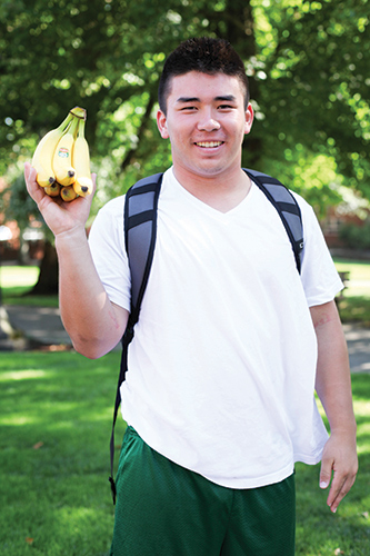 Student holding up an apple, showing the healthy food options at Pacific.