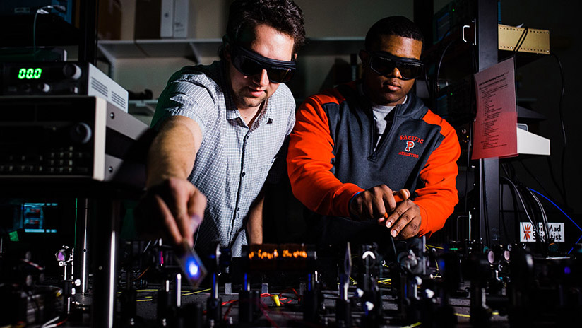 A student and professor work in the physics laser lab