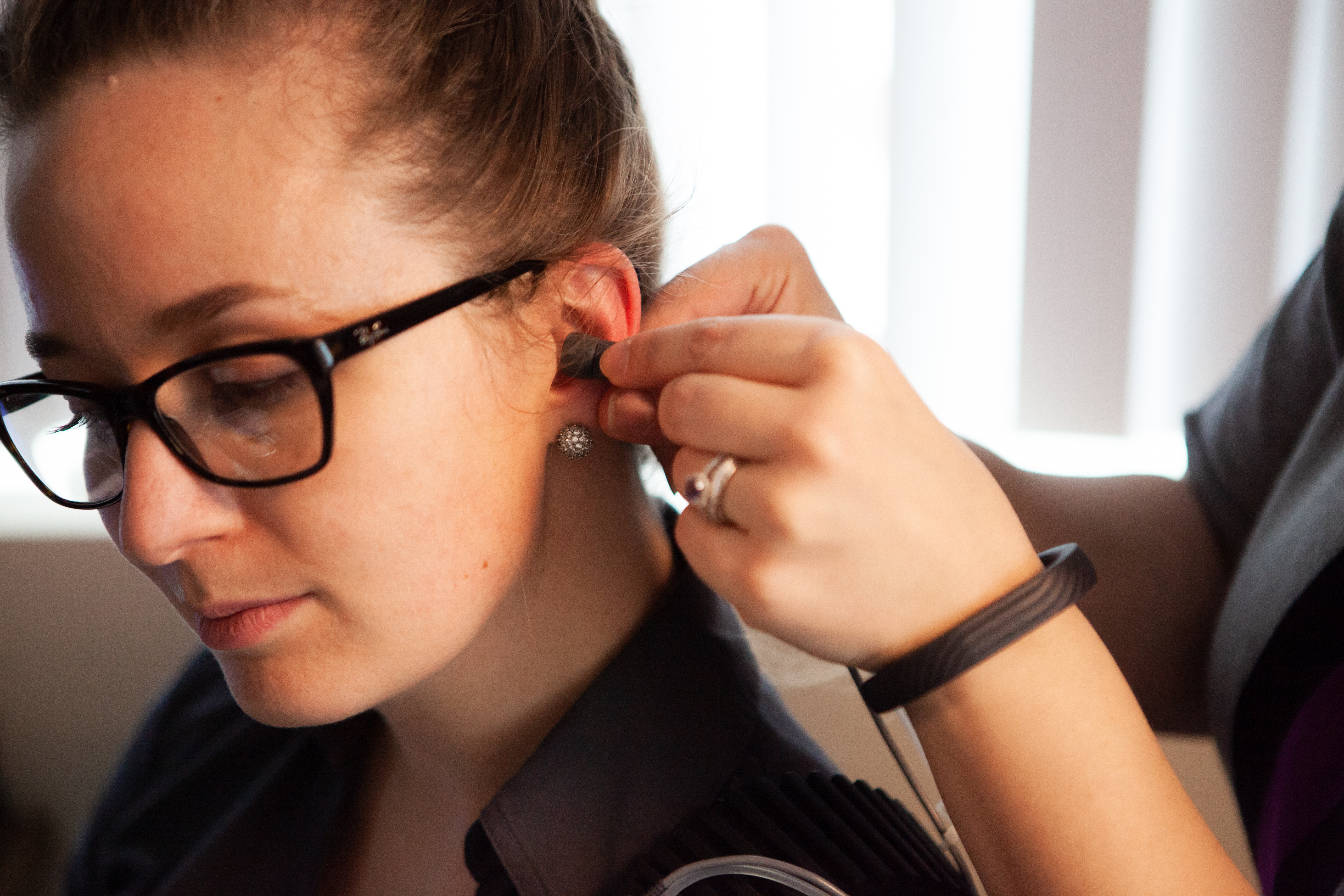 A hearing aid is placed into a patient's ear.