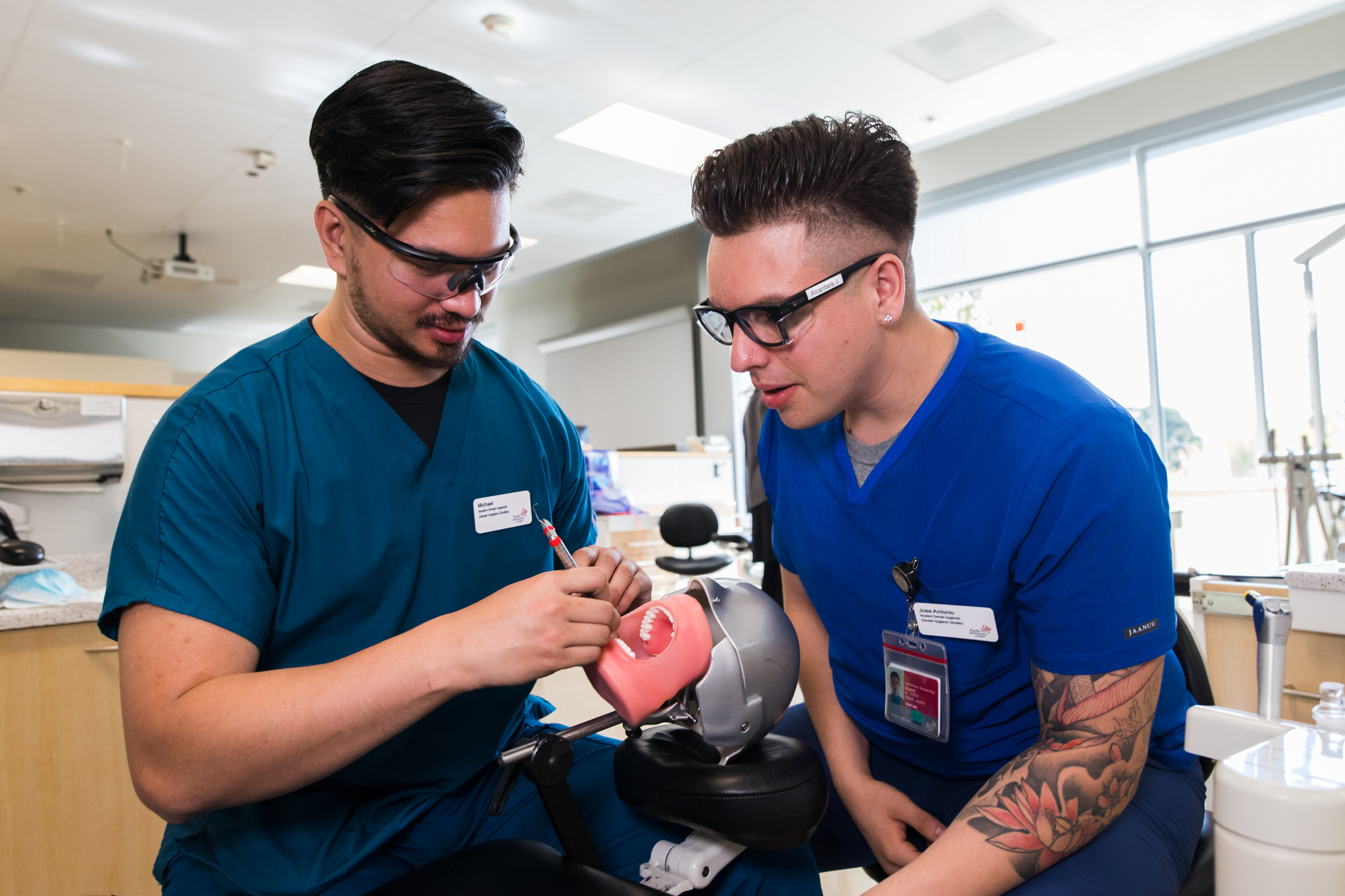 Two dental hygiene students practice cleaning techniques on a medical dummy.