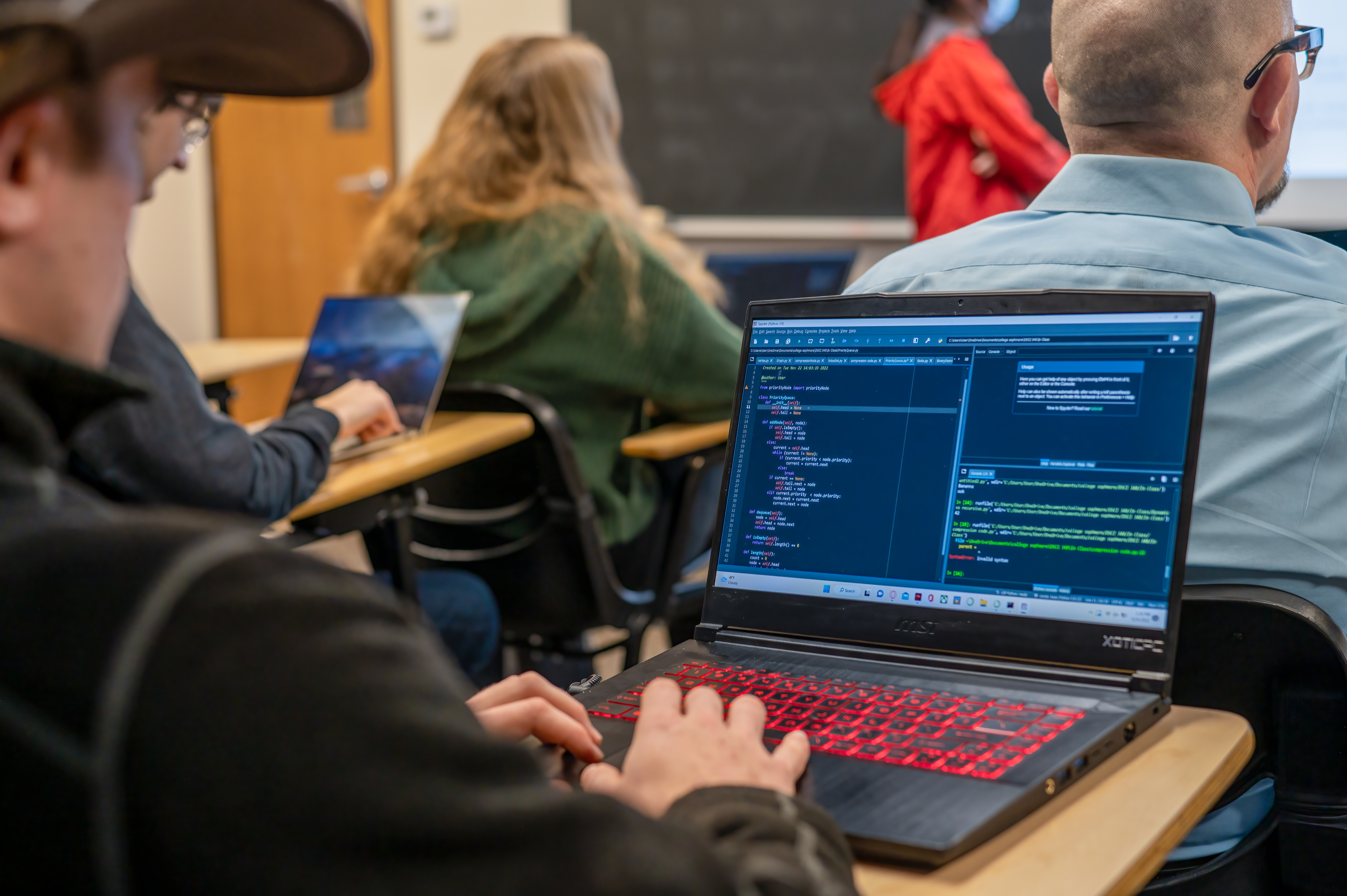 A student works on computer code while sitting in a classroom.