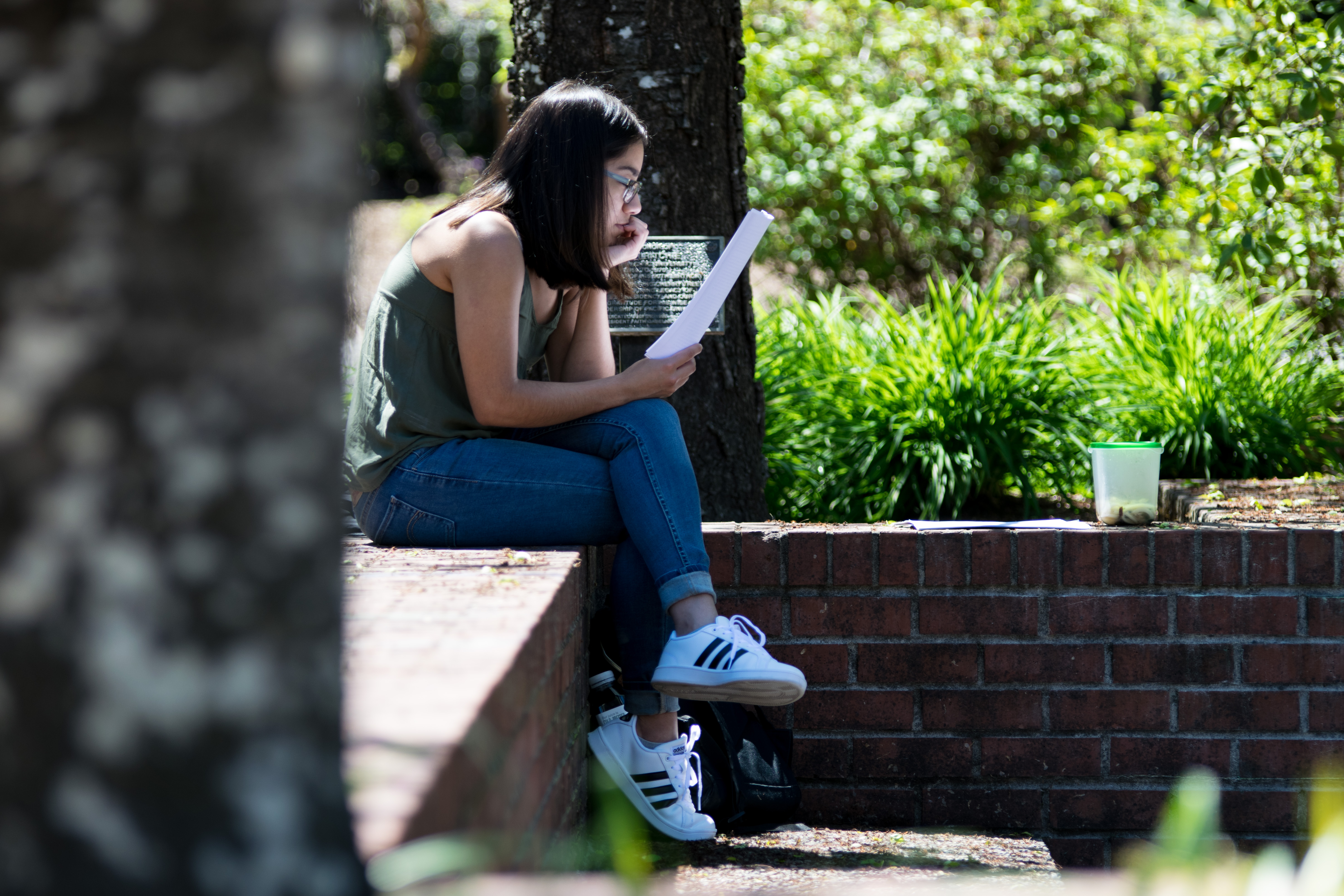 A Pacific University student sits in an outdoor campus space while studying.