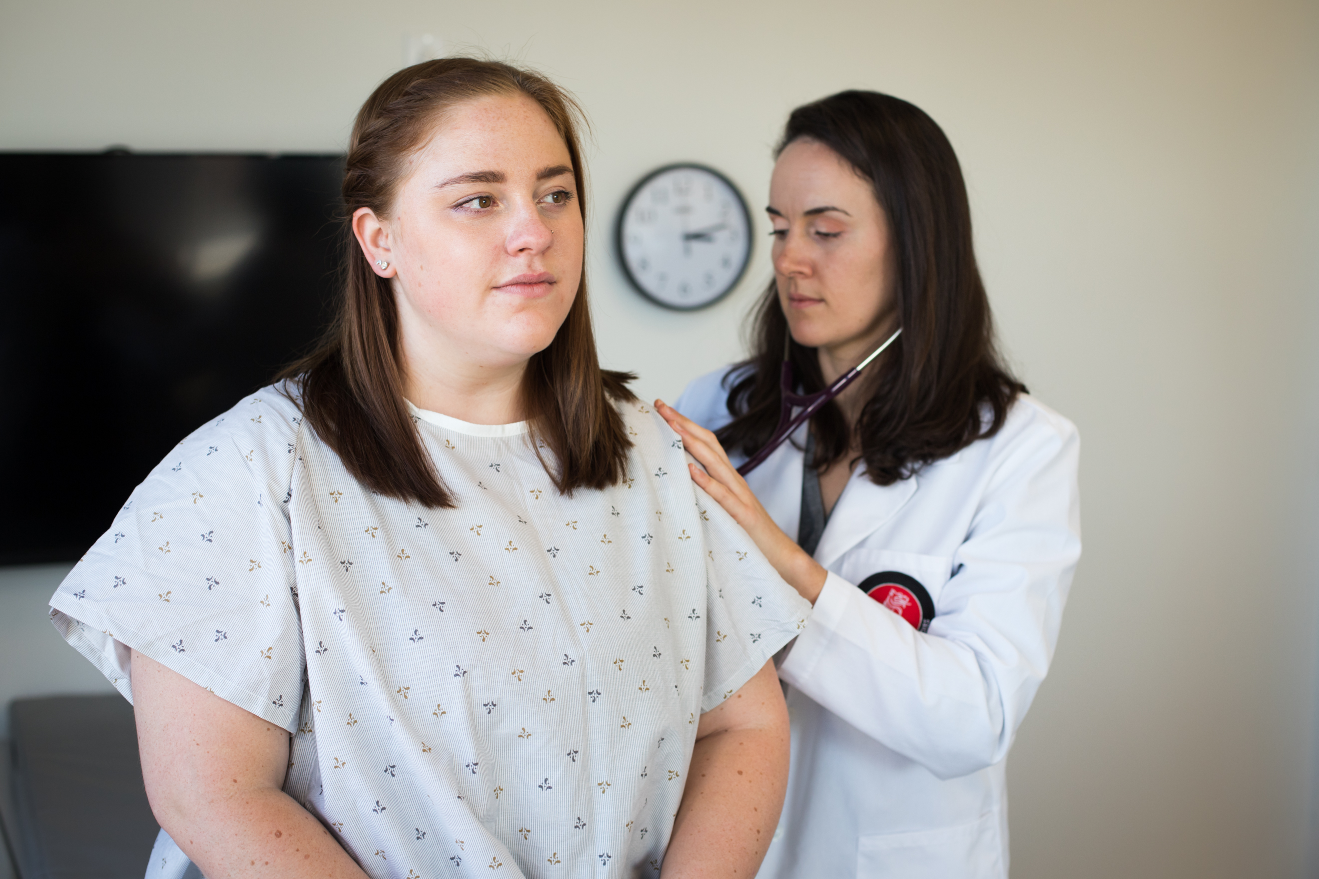A physician assistant studies student listens to a patient's lungs using a stethoscope.