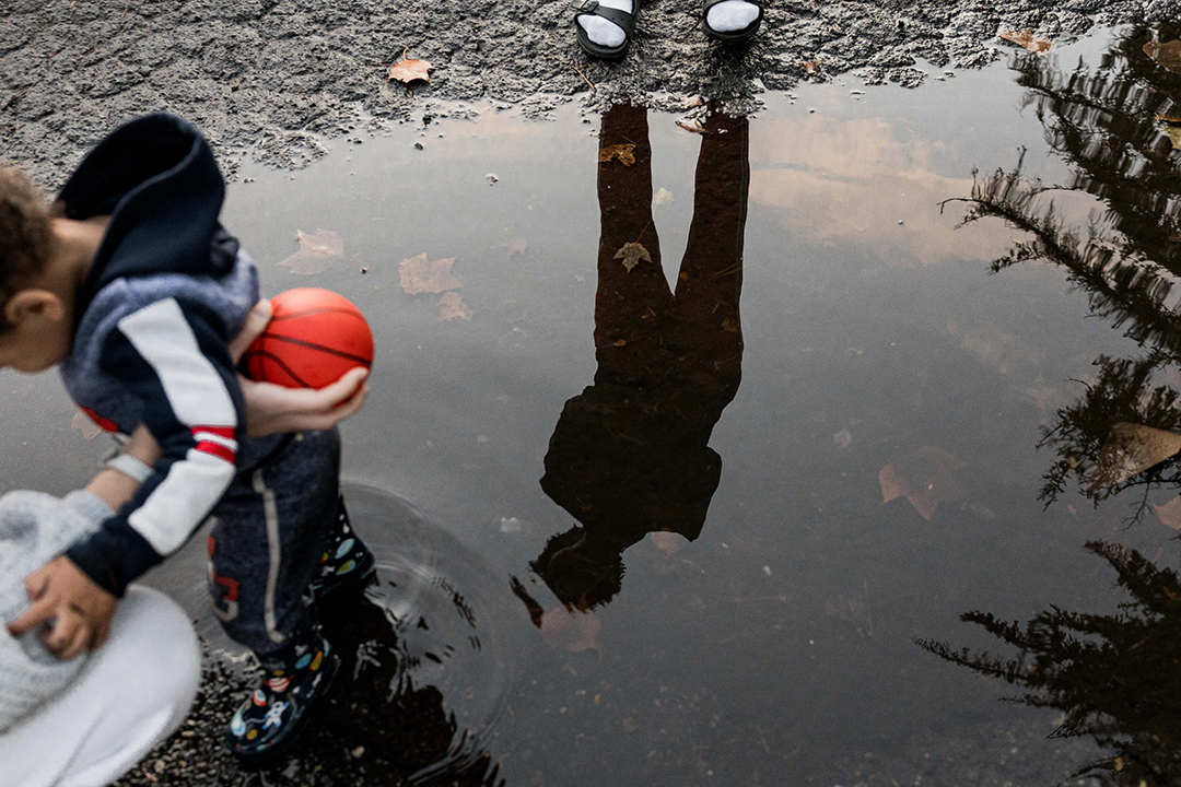 Rocket plays in the rain while Devin Fortune '25 looks on in reflection