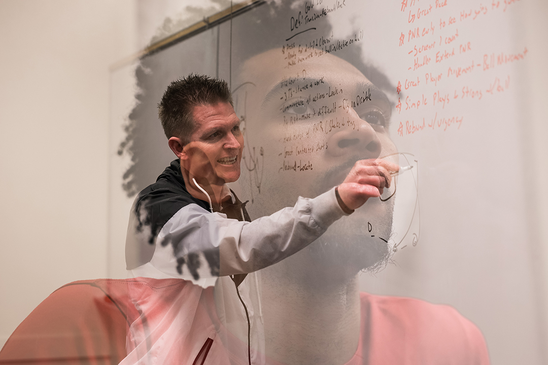 Image of Devin Fortune '25 superimposed on Boxer Basketball Coach Justin Lunt mapping a play on a whiteboard