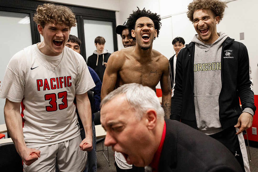 Members of the Boxer men's basketball team, including Devin Fortune '25, center, celebrate after the team beat Whitworth to make the conference playoffs for the first time in 25 years