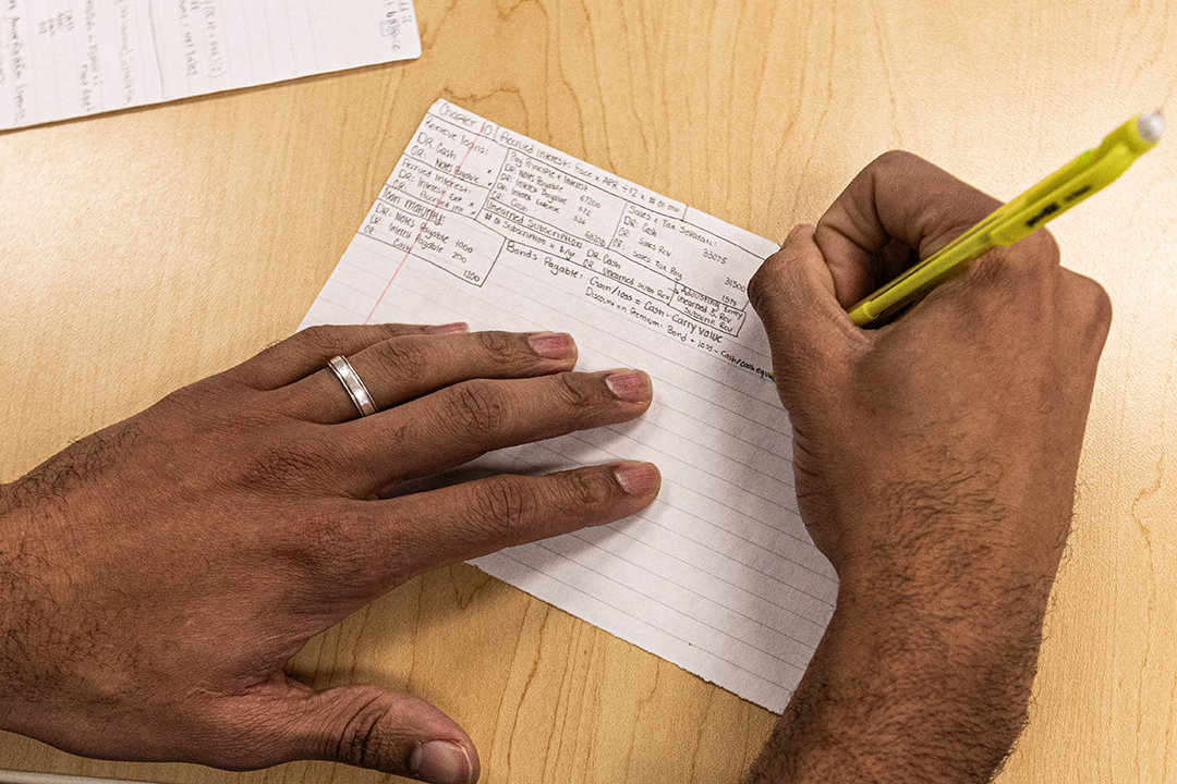 Devin Fortune '25 writes notes on an index card while studying for an accounting exam