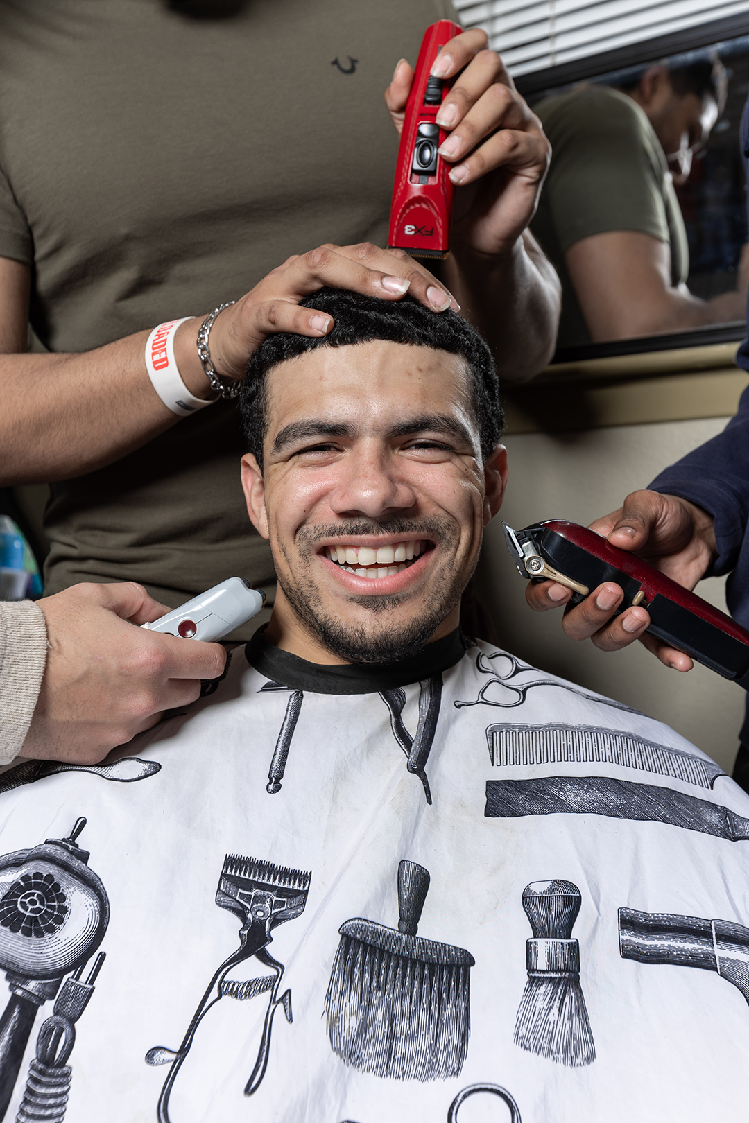 Jay Fordham '25 poses as friends surround him with hair-cutting equipment