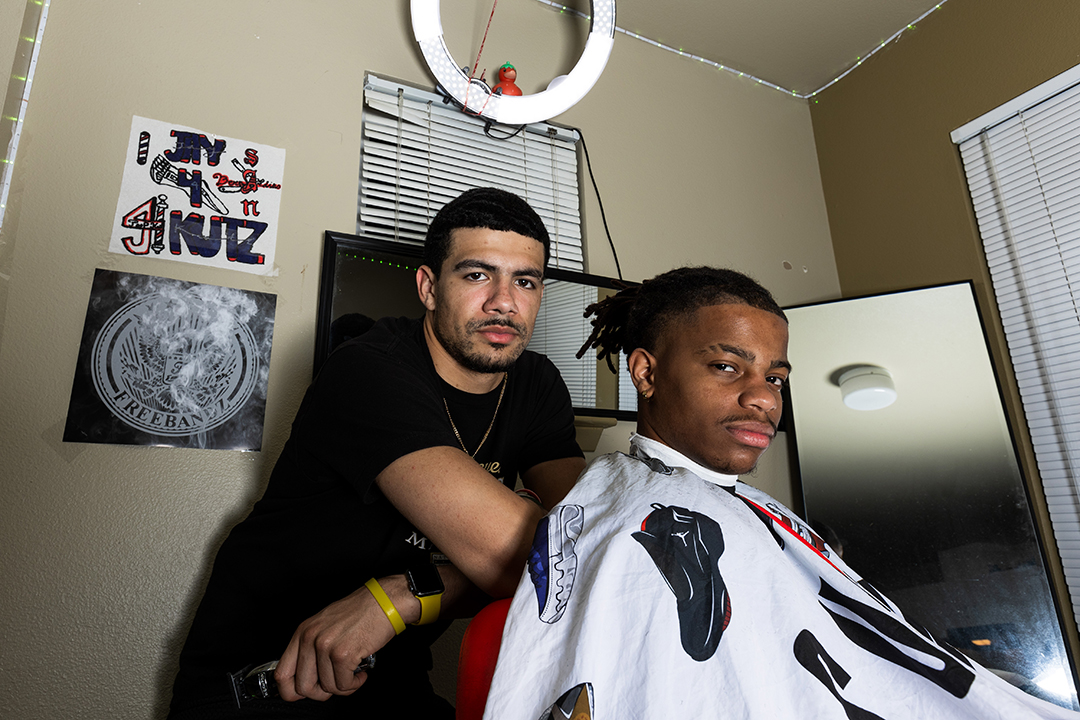 Jay Fordham '25 stands behind Ray Pruitt '25, who sits in a barber chair