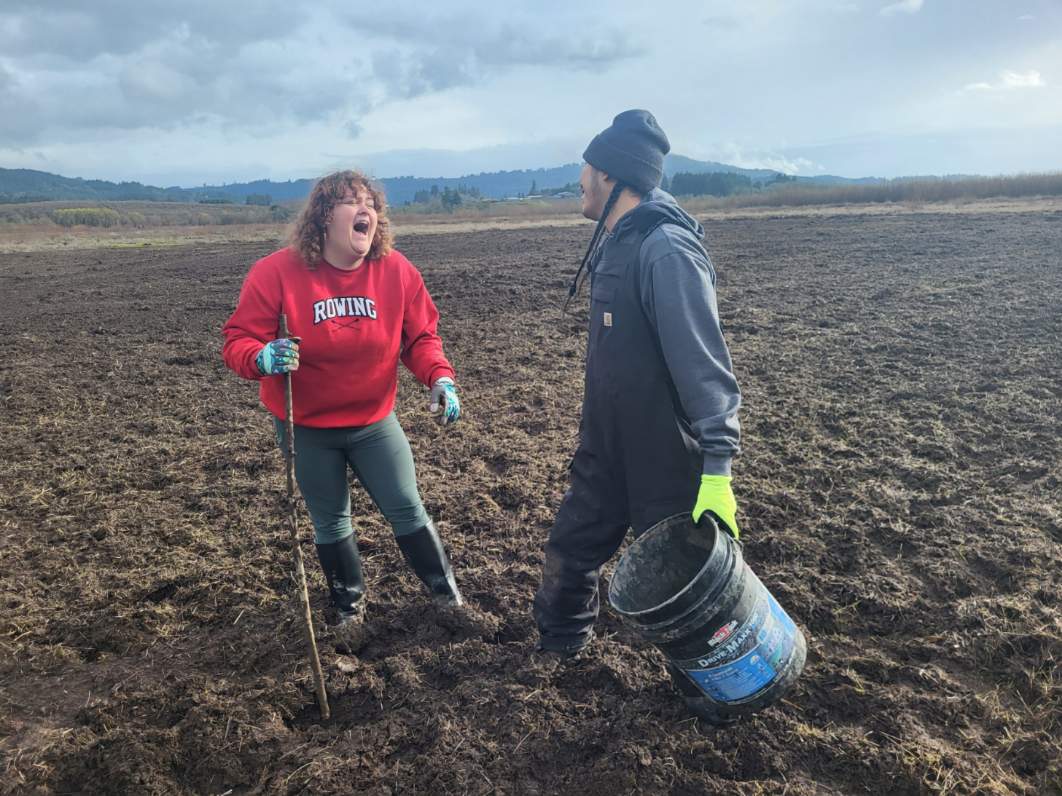 Students having fun in the mud of Lake Wapato while replanting the indigenous root.