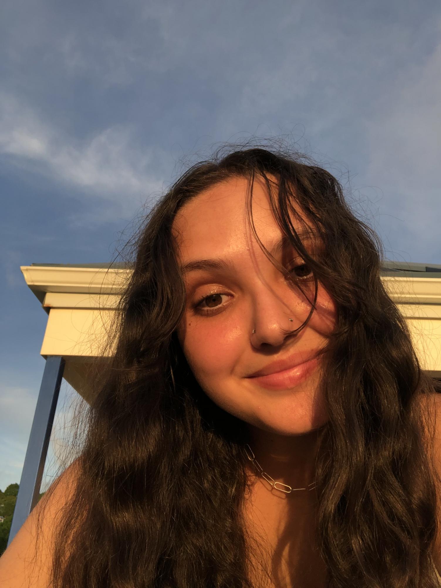 Photo of woman with long dark hair with blue sky in background