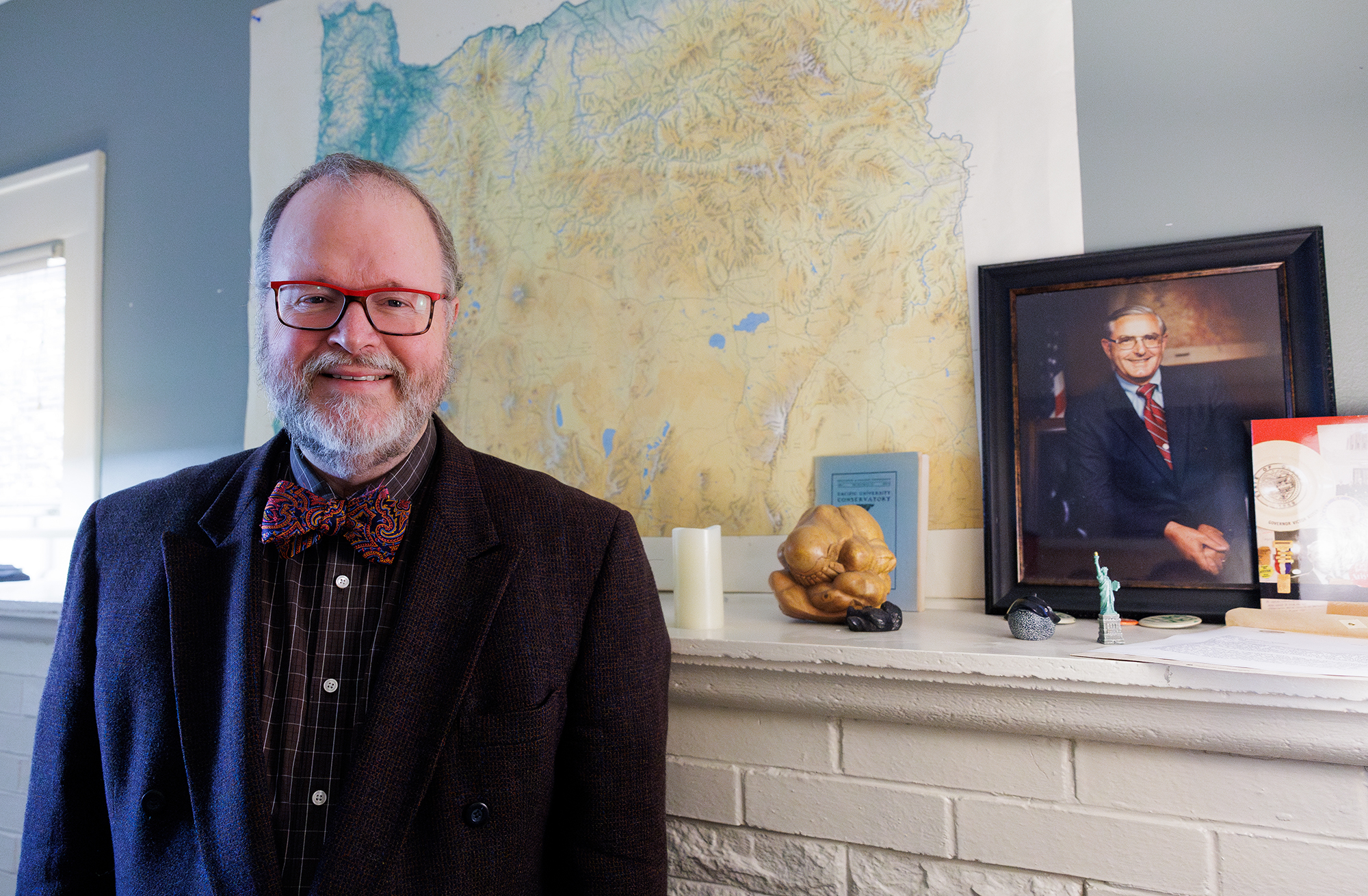 Jim Moore Standing In His Office In Front Of A Large Oregon Map