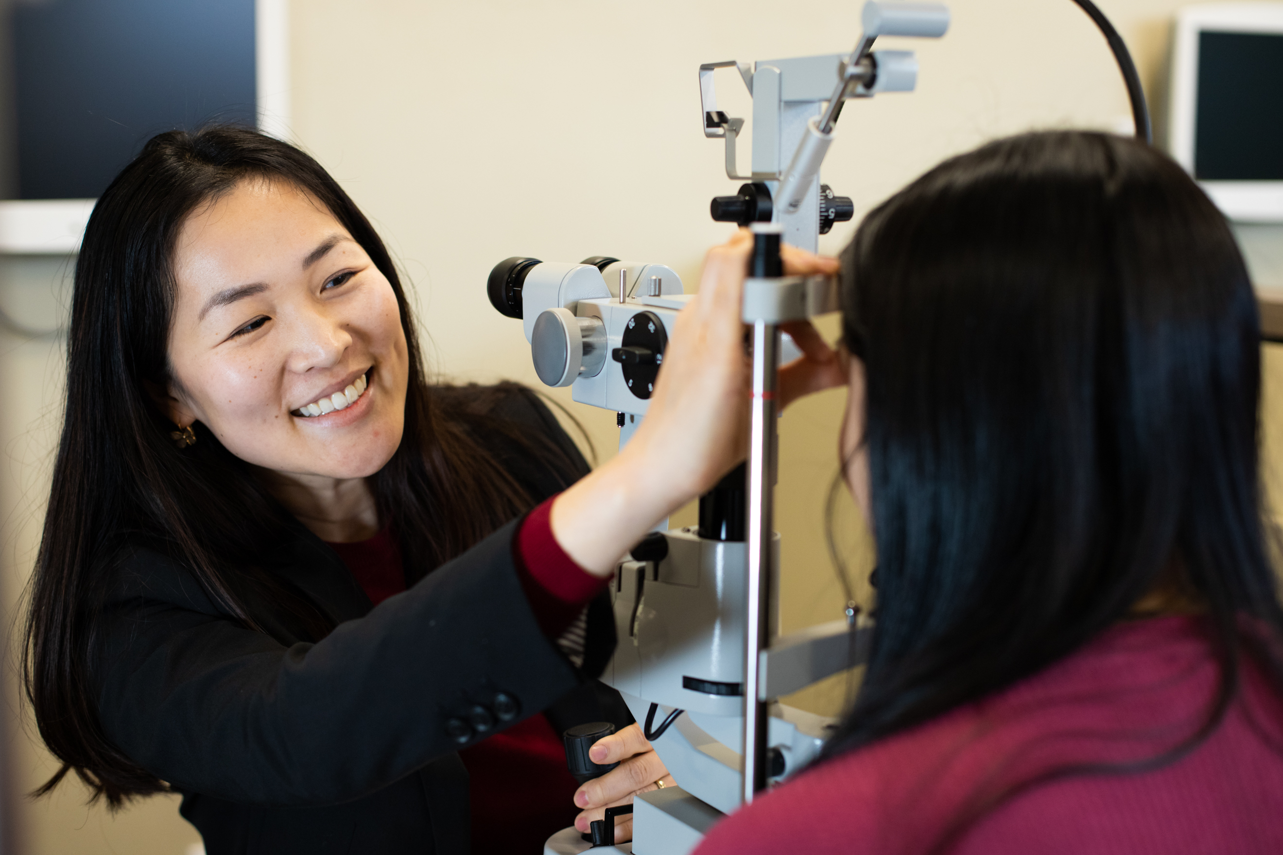 An optometrist in training examines a patient's eyes in a clinic.