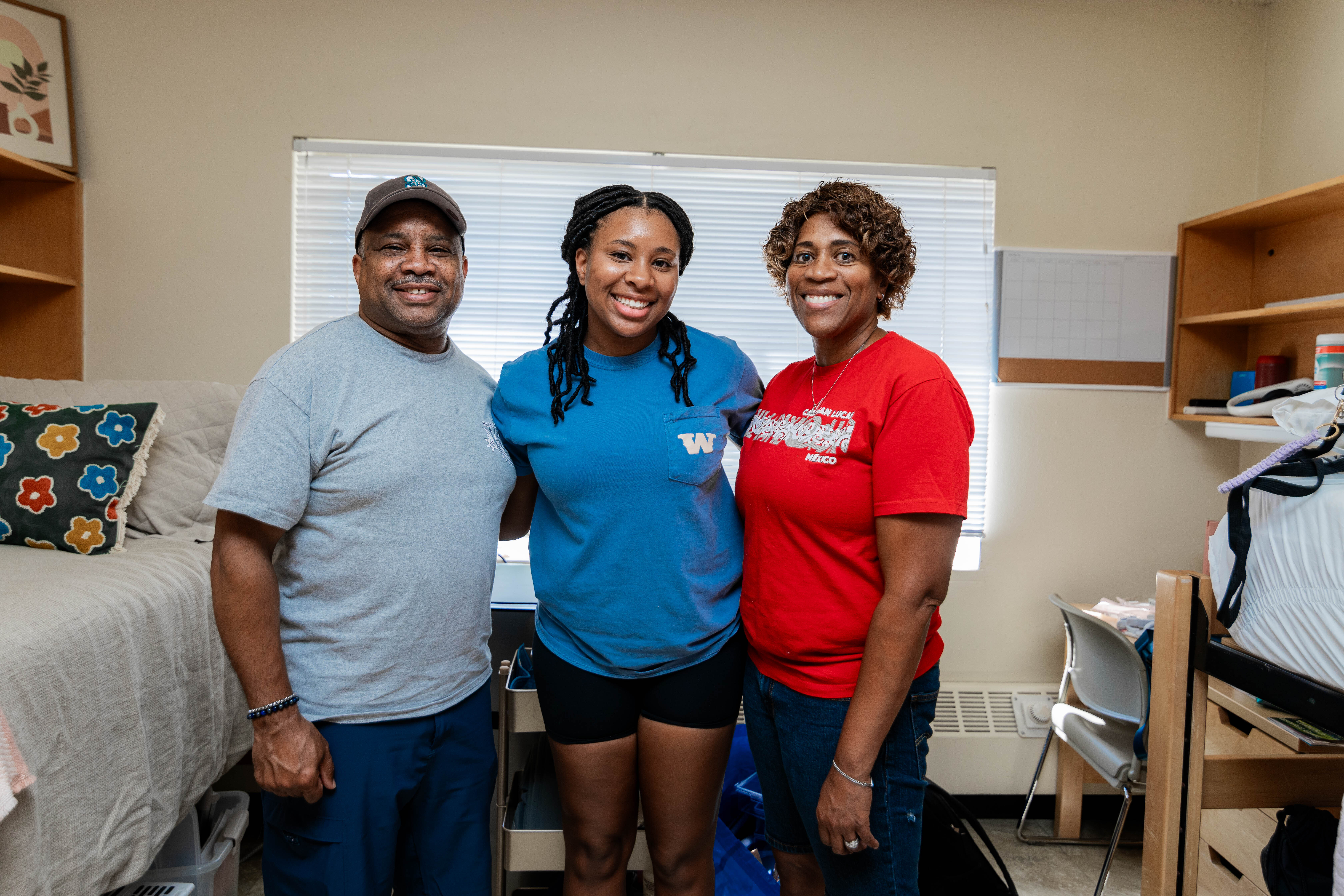 A student poses with their guardians while moving into the dorms during orientation.