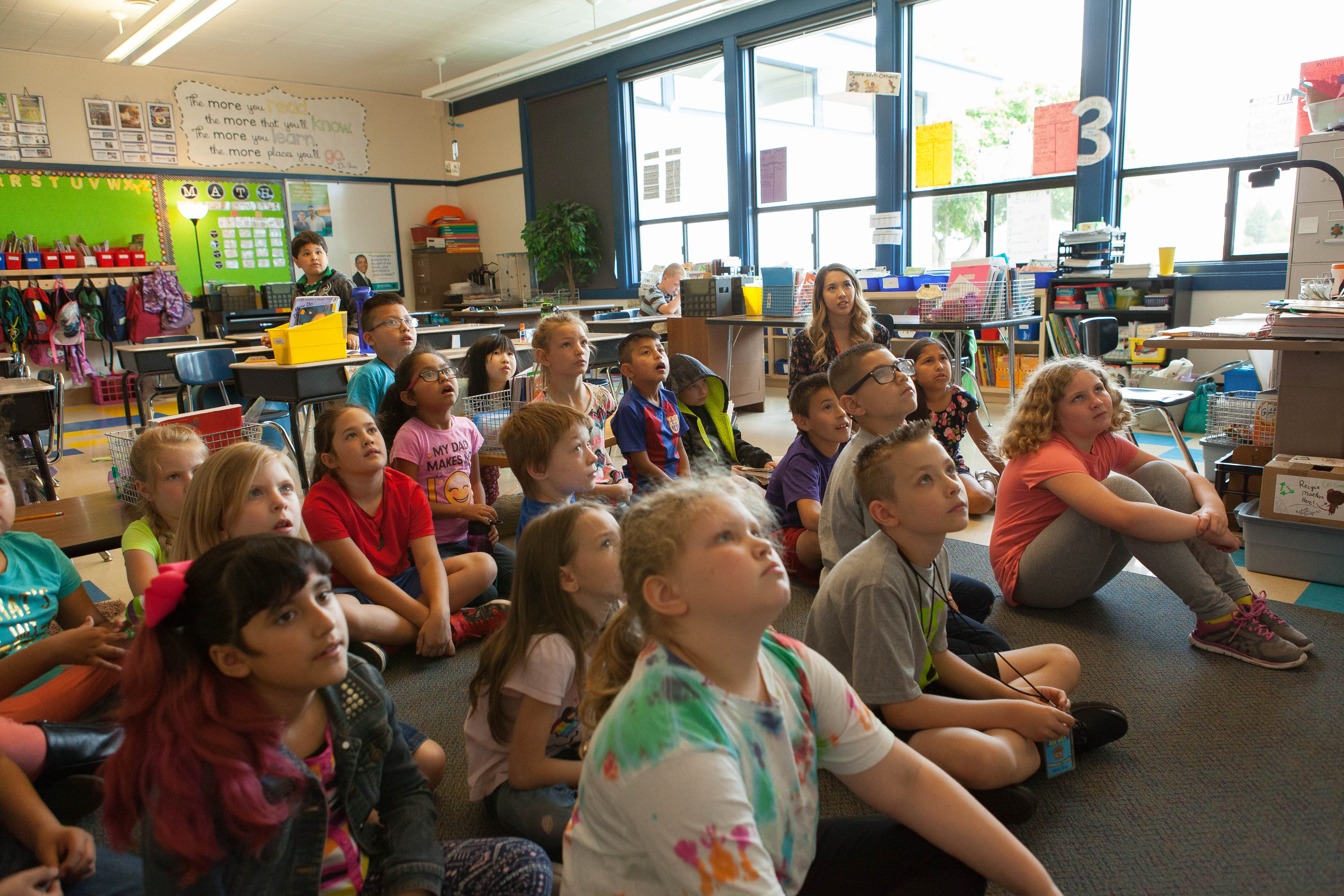 A College of Education graduate sits with their elementary school class. 