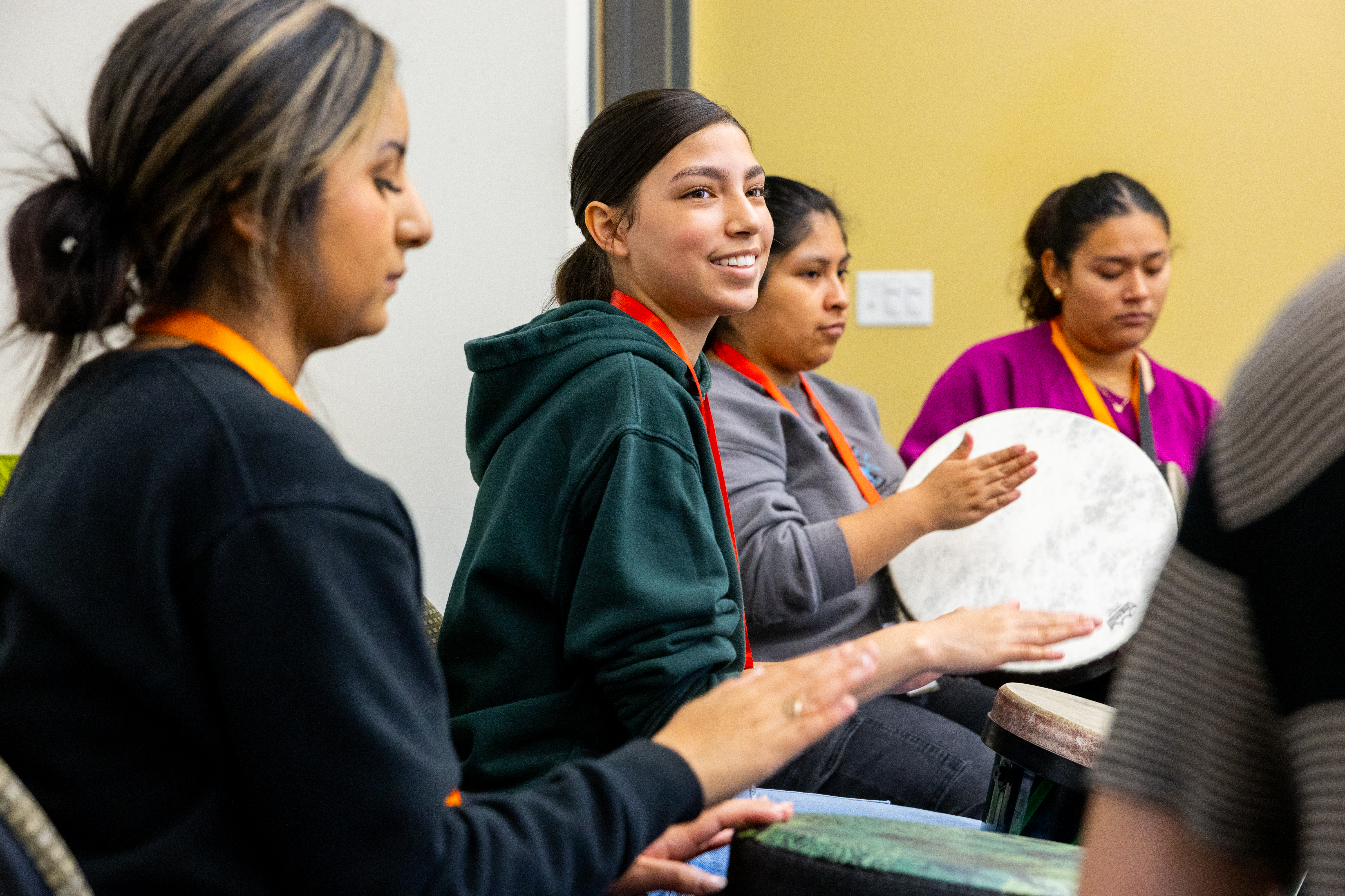 Several students participate in a drum circle.