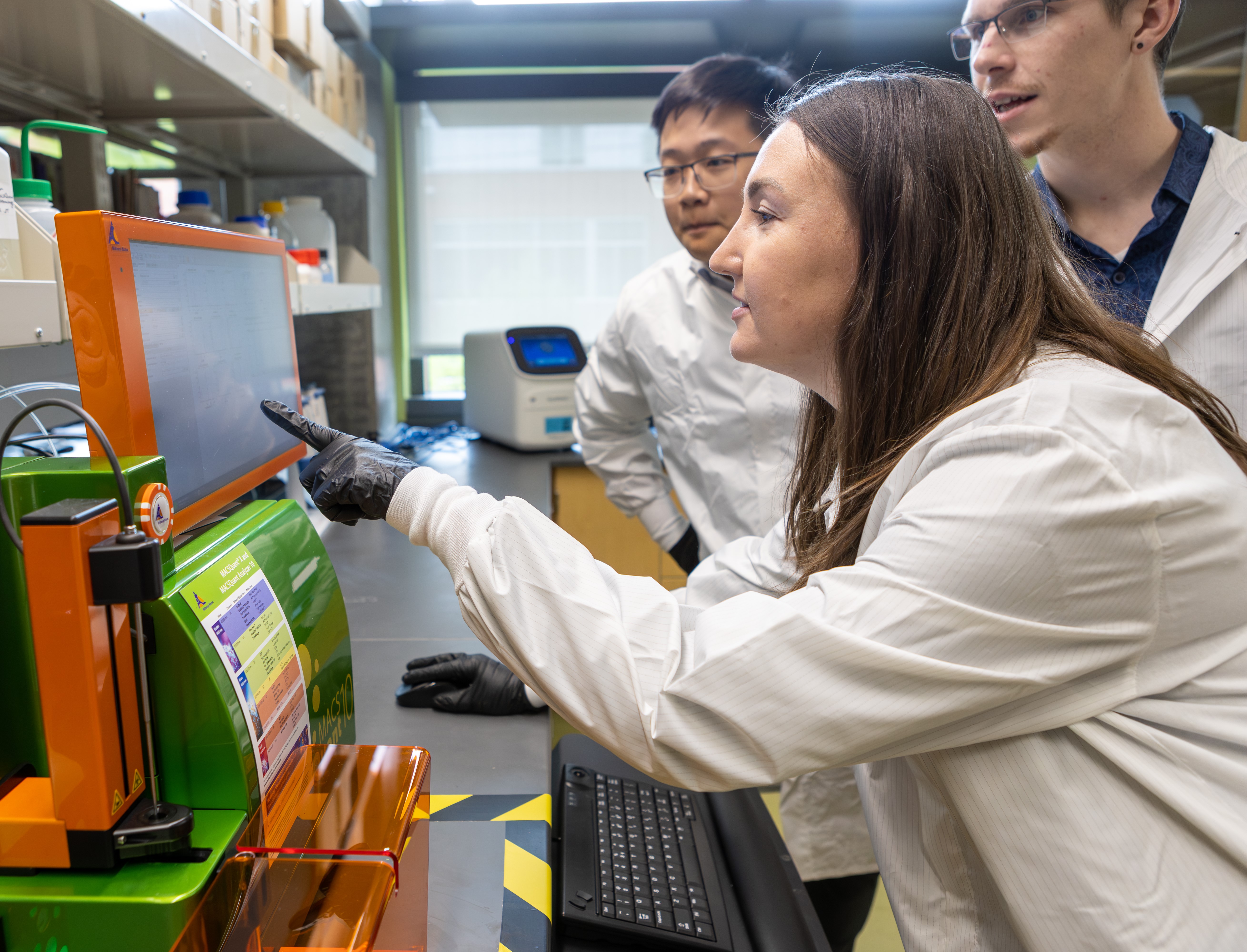 Three pharmacy students examine the results of lab work on a computer monitor.