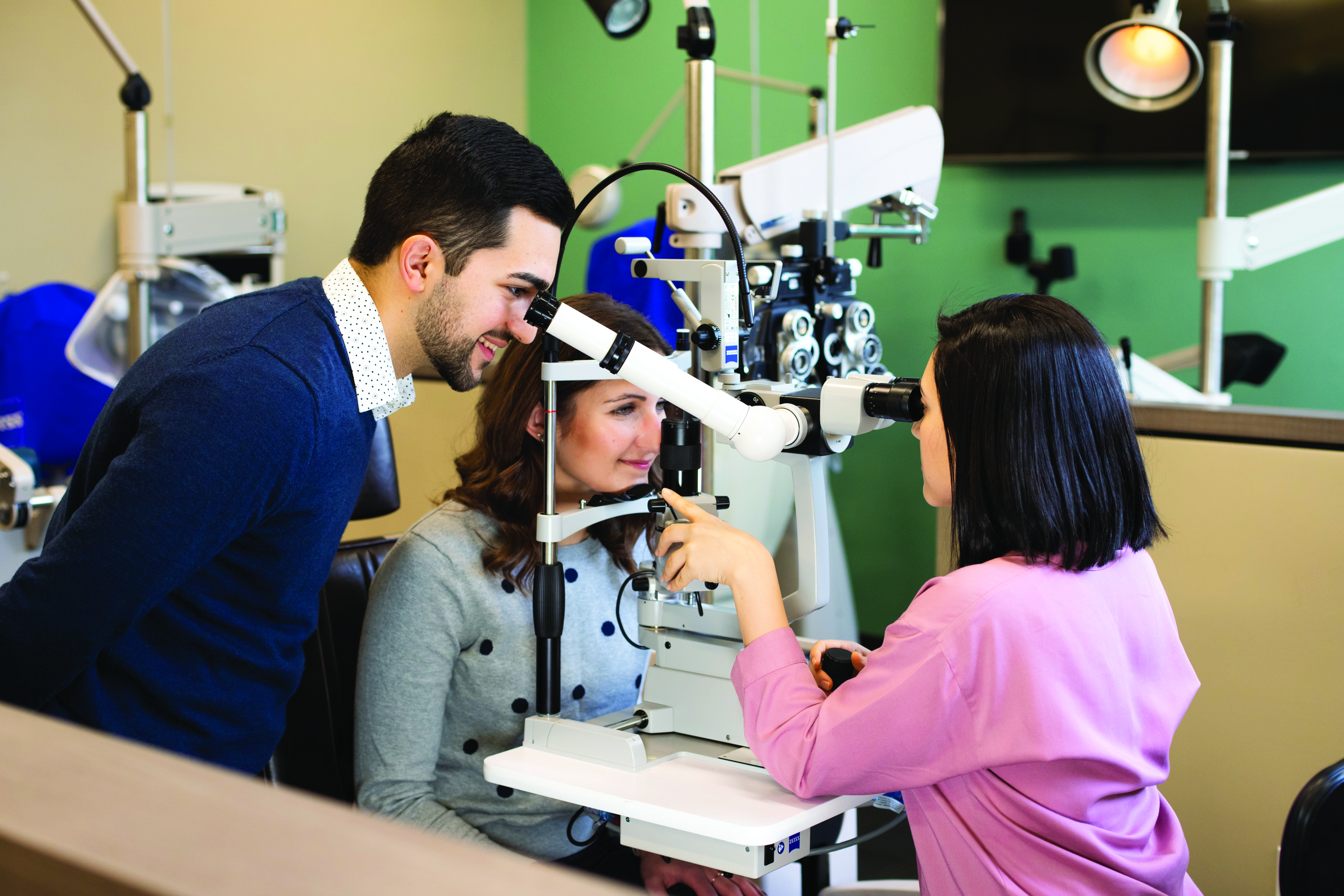 Two optometry students examine a patient's eyes during a routine exam.
