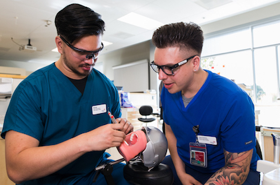 two dental students practicing on an oral model