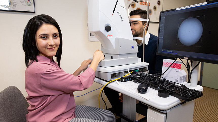 A Pacific University optometry student practices an eye exam with a model patient