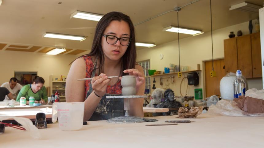 A Pacific student works with clay in an art studio