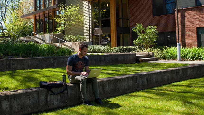 Student with laptop in lawn