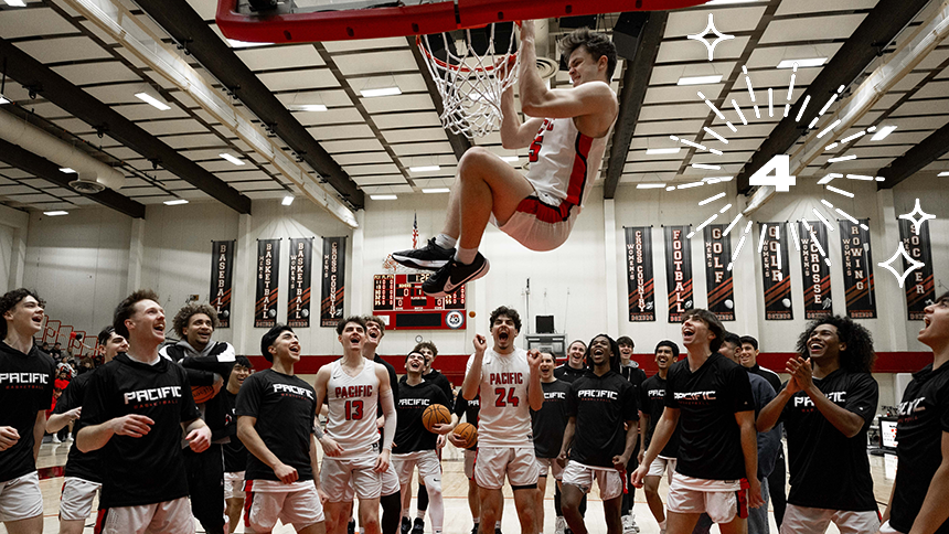 The men's basketball team celebrates as one player hangs from the rim