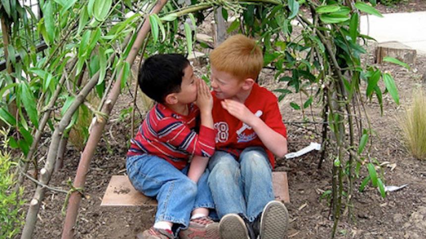 Children sitting together in a garden talking to each other. 