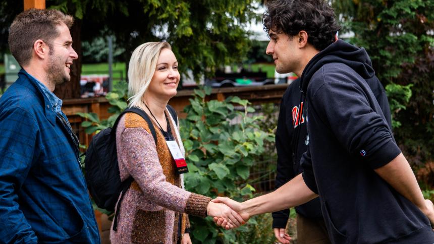 A current Pacific undergraduate students greets two alumni during Homecoming weekend.