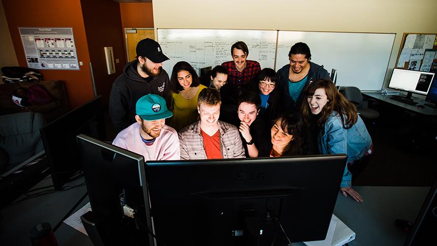 Students and professor huddled around computer screen in computer science class