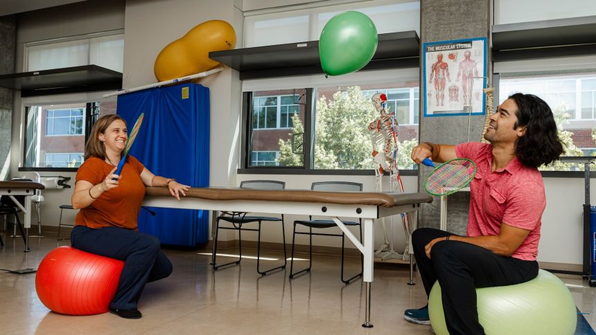 two occupational therapy students doing an exercise with rackets and balloons