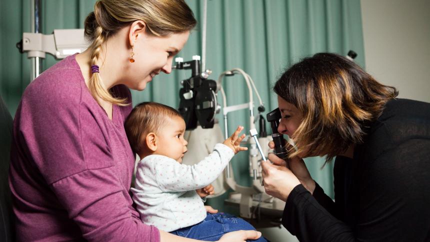A mother has her baby's eyes checked by an optometrist. 