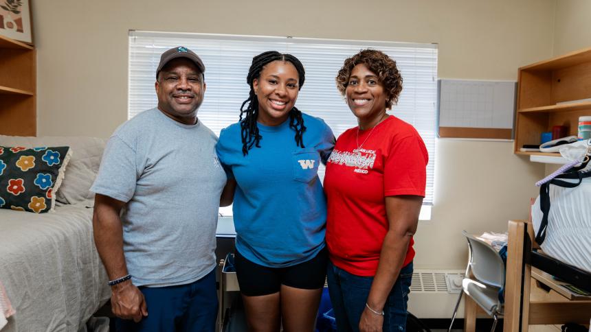 A student poses with their guardians while moving into the dorms during orientation.