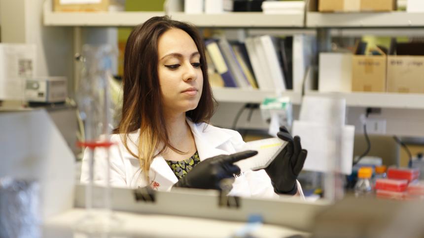 A pharmacy student dispenses chemicals into a pipet tray.