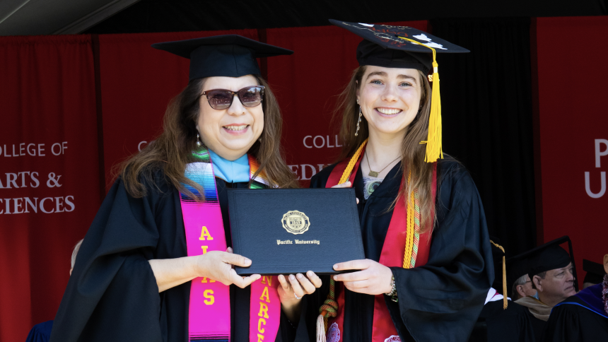 Alex Hays receives her Pacific University diploma on stage with Narce Rodriguez