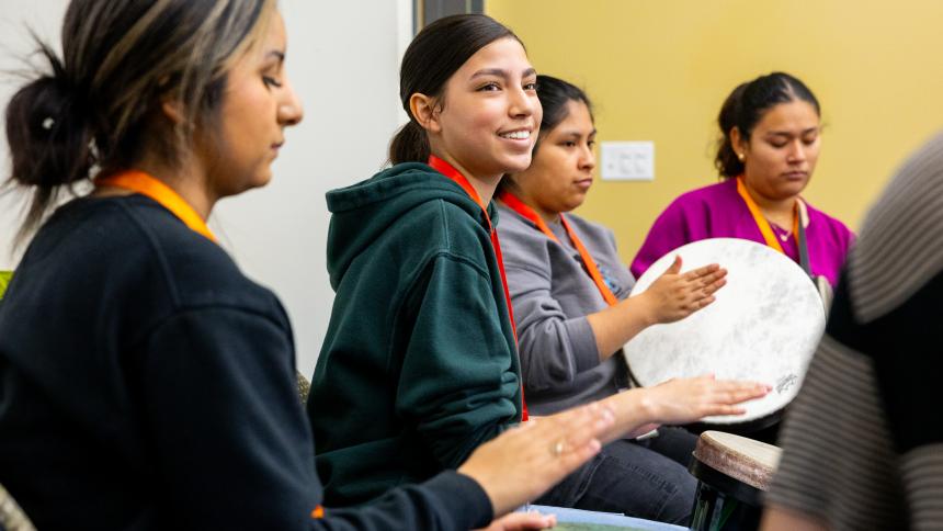 Several students participate in a drum circle.