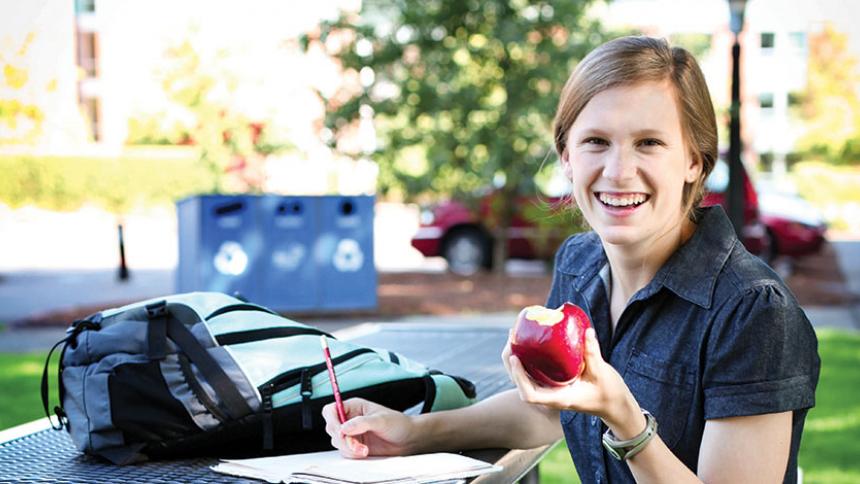 Female Smiling holding an apple. 