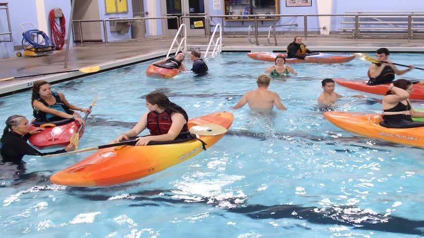 Students attempt kayak skills in the pool with careful watch by instructors. 