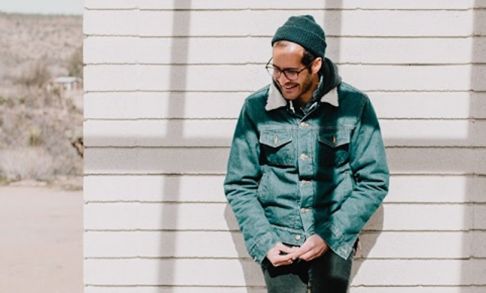 Anis Mojgani Leaning Against Wall, Wearing Winter Coat