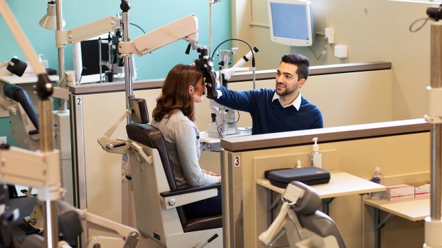 Student using eye examining equipment on someone