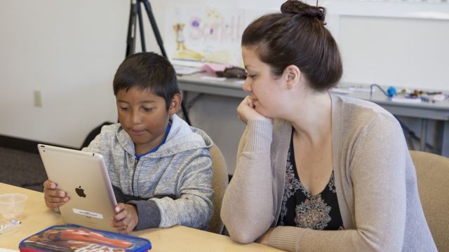 teacher helping a student on a tablet