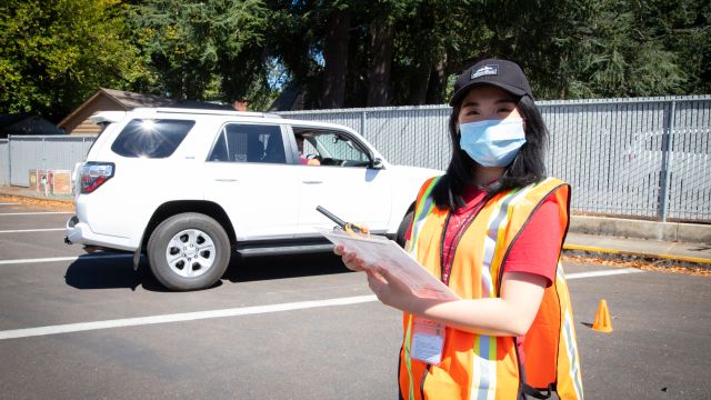 A masked Pacific employee in a parking lot with a clipboard and safety vest