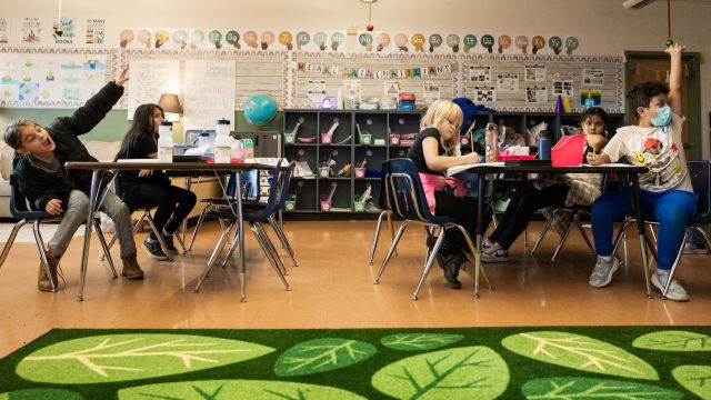 students in a classroom raising their hands