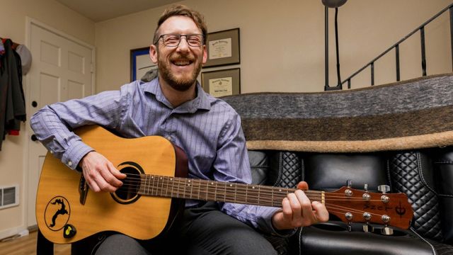 Cody Mills Playing The Guitar In His Home