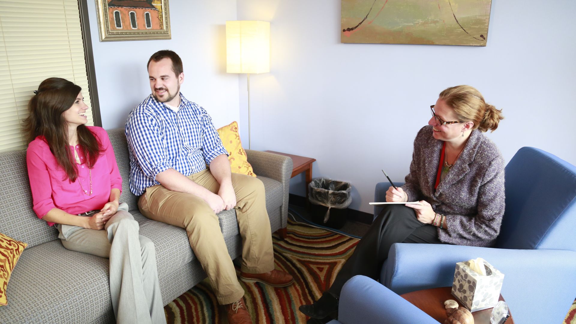 three people talking on sofas